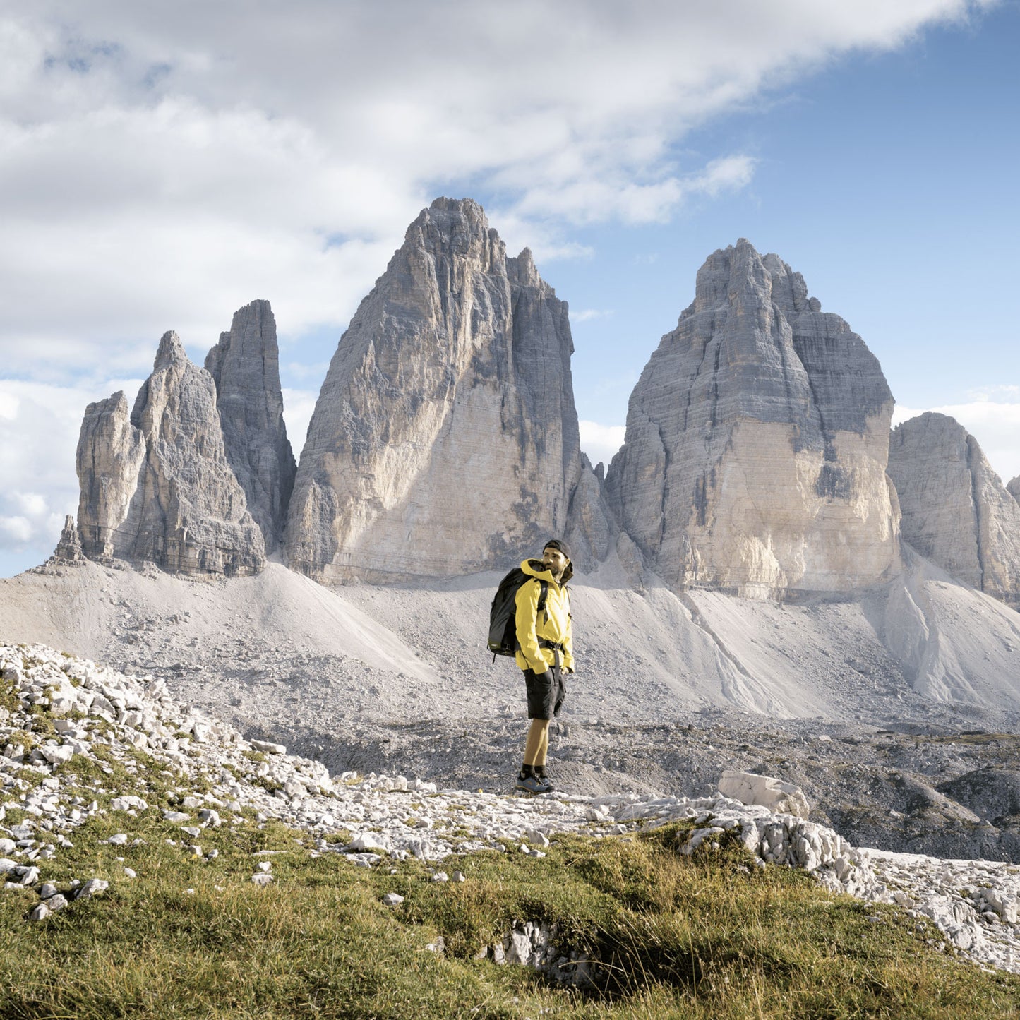 A man wearing a backpack looking sideways, and mountain range scenery in the background 