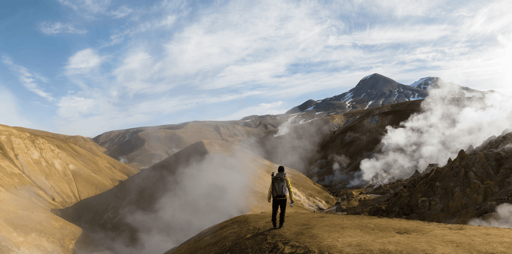 Man with a camera backpack hiking and viewing mountains