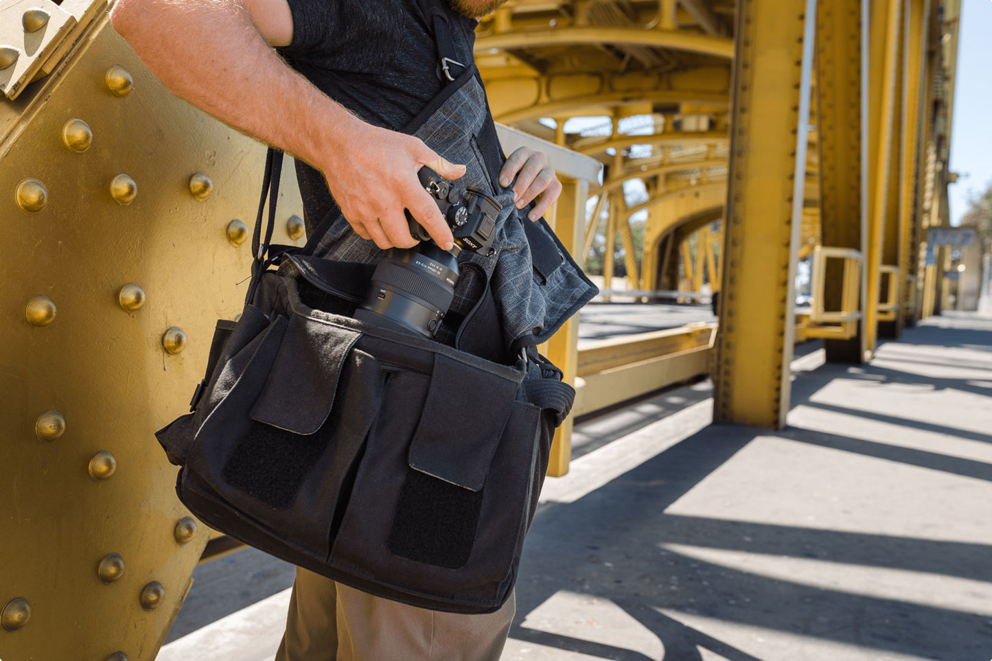 A photographer reaching into a black camera bag and grabbing his camera gear out