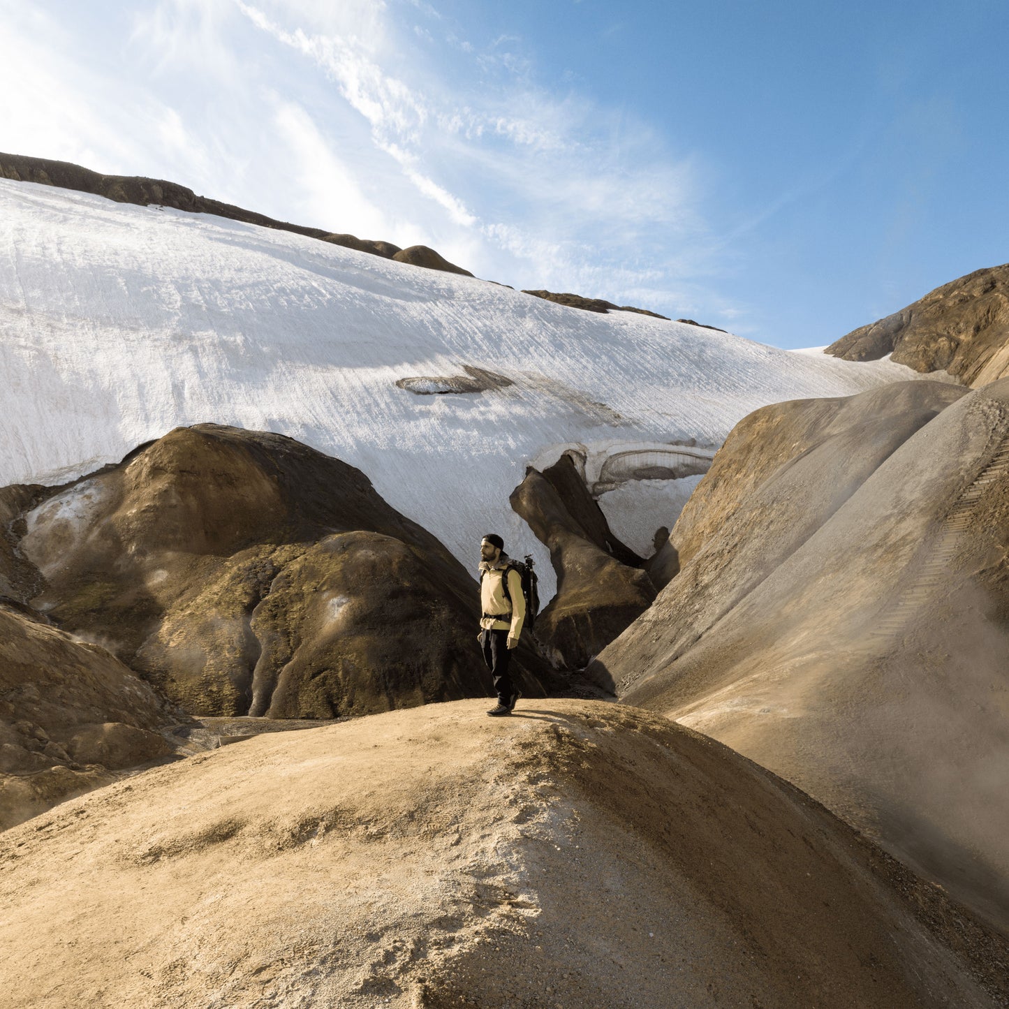 Highlands of Iceland scenery with a man standing on a boulder wearing a backpack