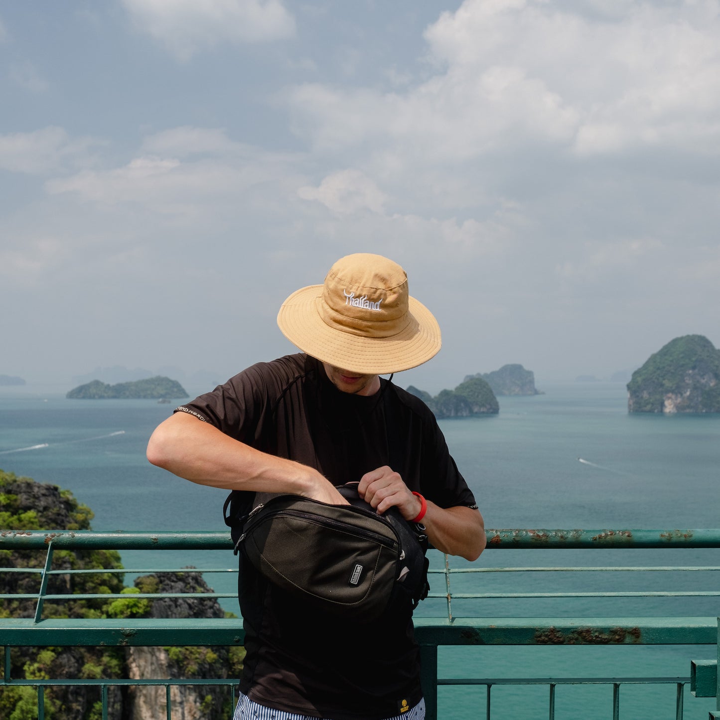 A man reaching into a black bag to grab something out, with ocean scenery background